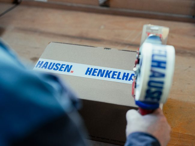 Henkelhausen Mitarbeiter klebt Paketband auf Versandkarton