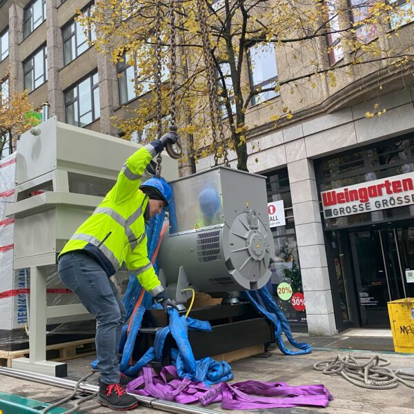 Mitarbeiter befestigt Aggregat am Kran